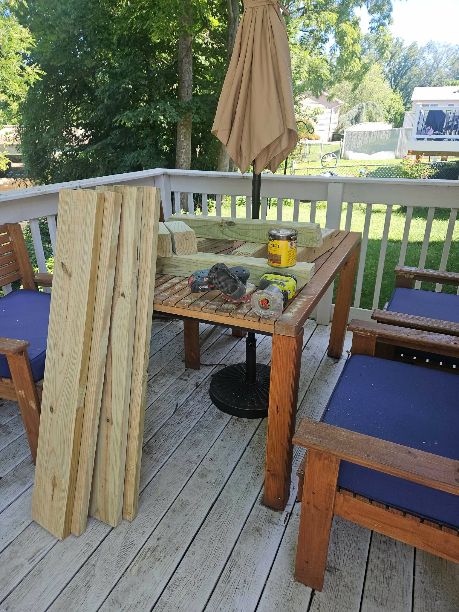 Cut lumber pieces, stain can, and sanders staged on the deck