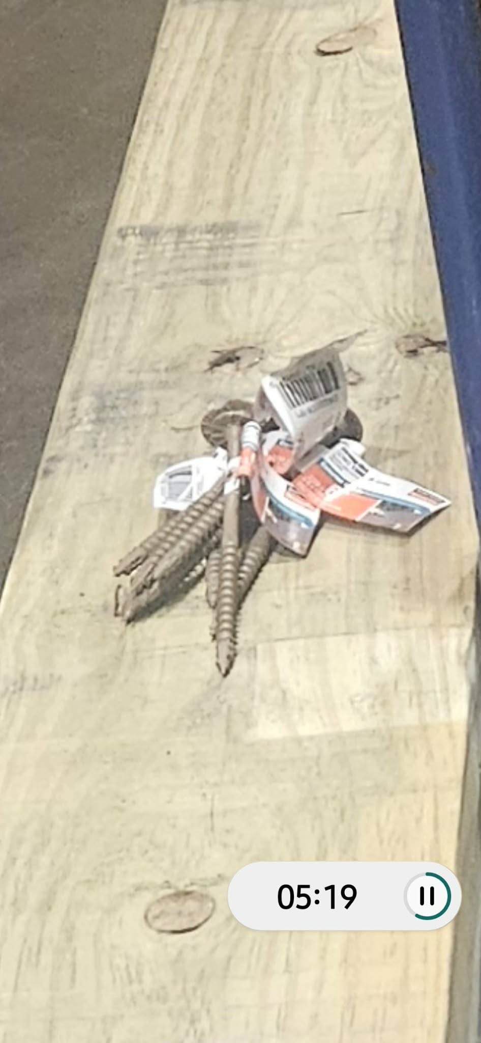 Deck screws and hardware tags resting on a piece of lumber