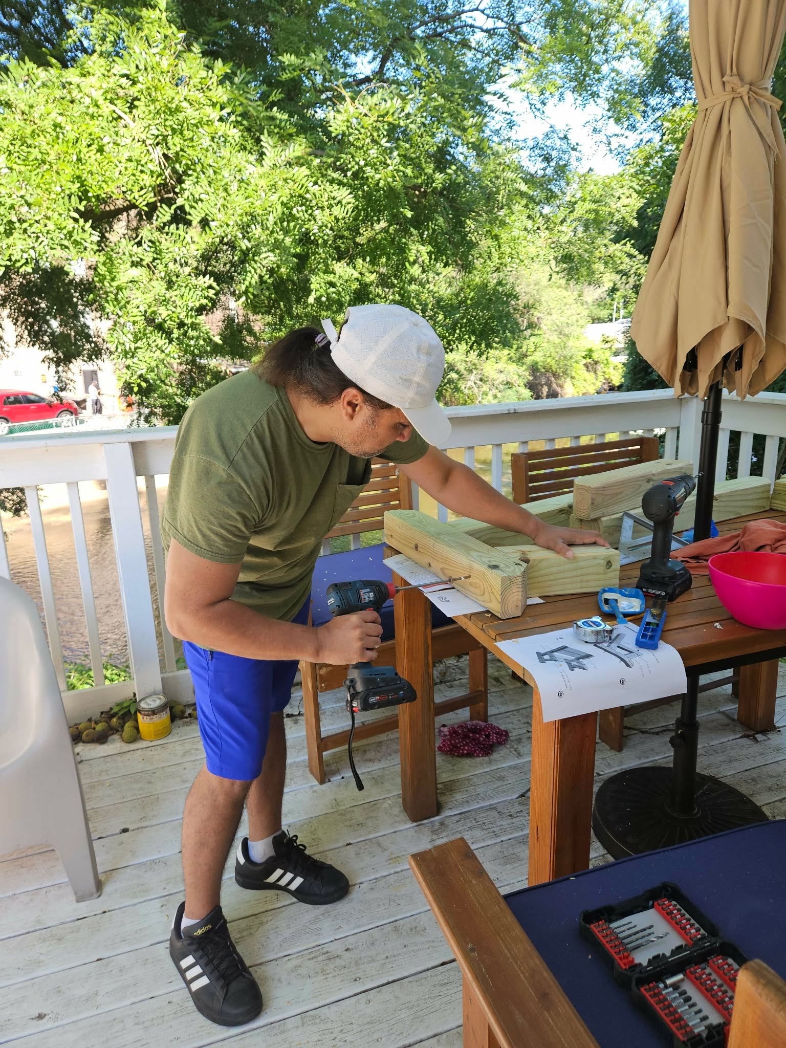 Drilling pocket holes into a board with the printed plan sheet on the table