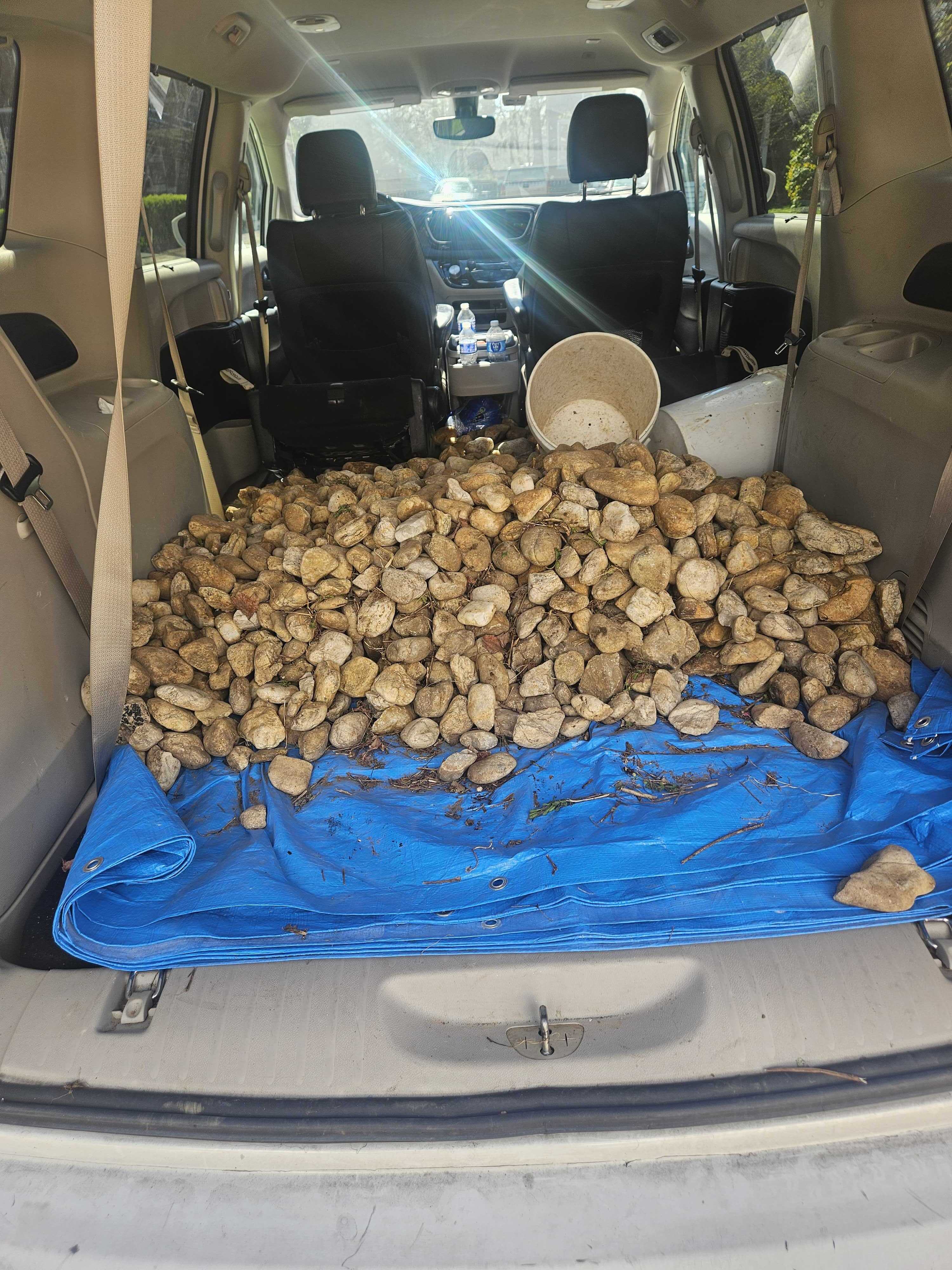 River rocks loaded in the back of the minivan on a blue tarp