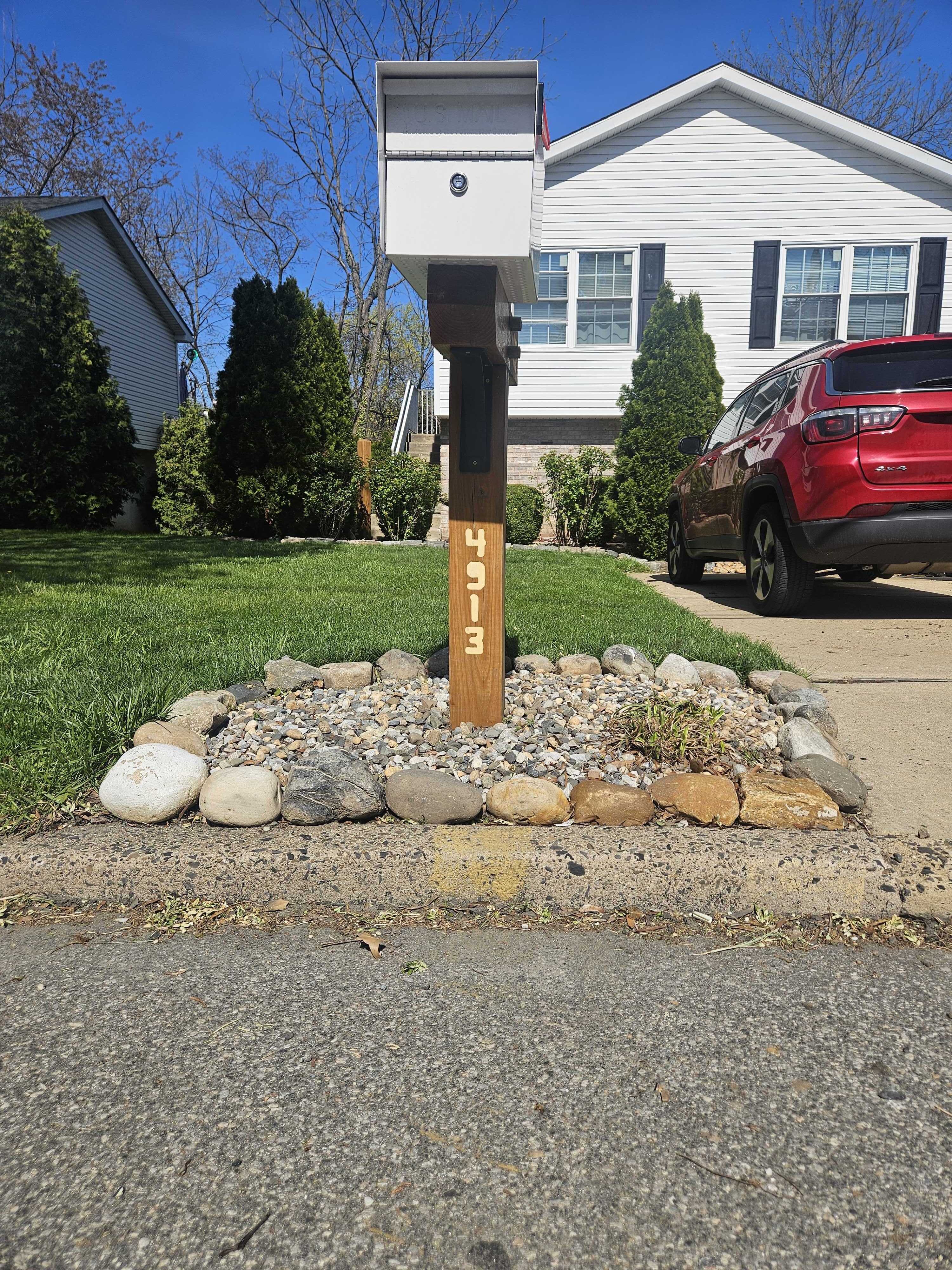 Mailbox base with large river rocks as border and river rock fill