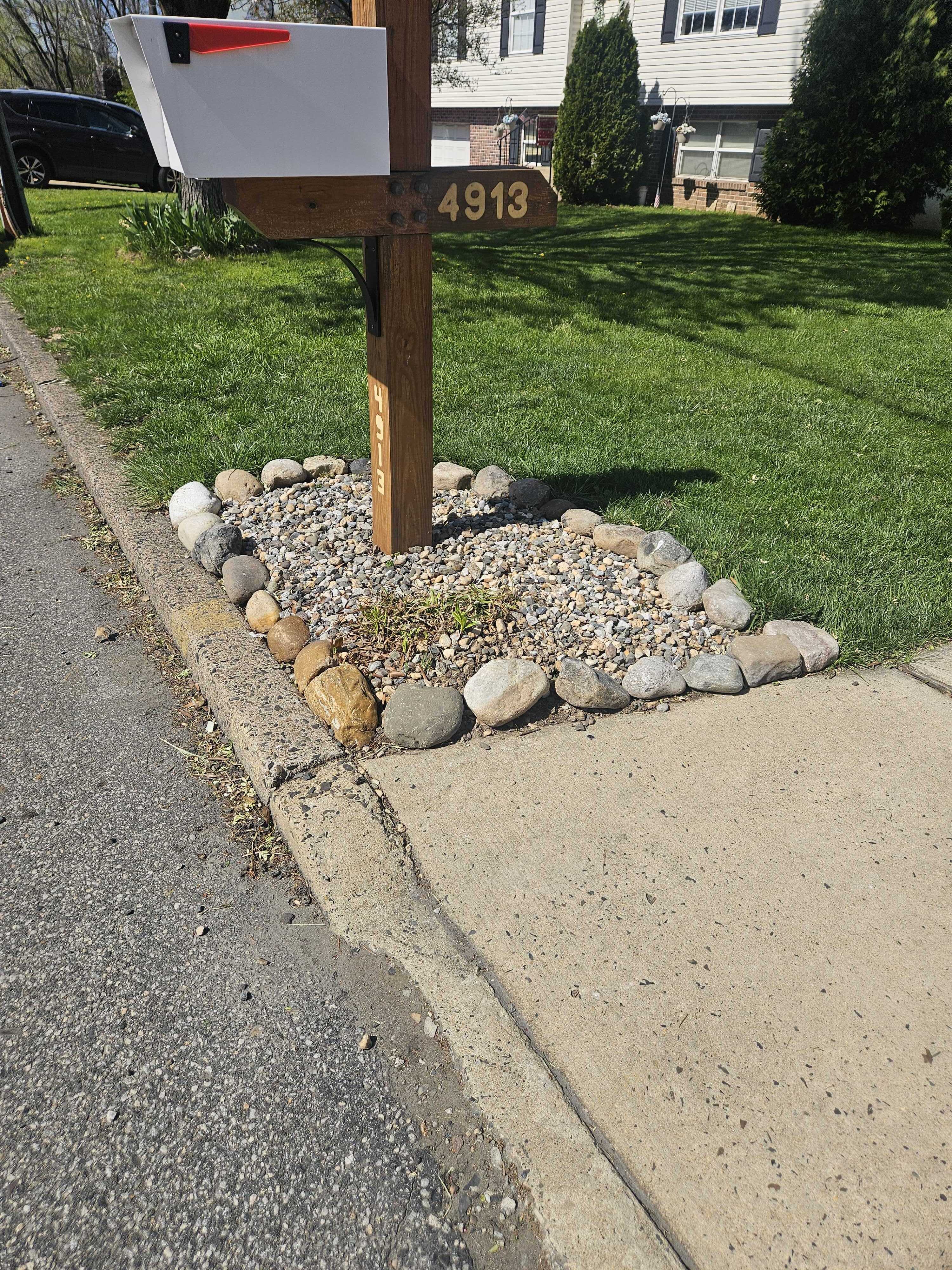 The mailbox post and rock base from street level — the finished front of the property