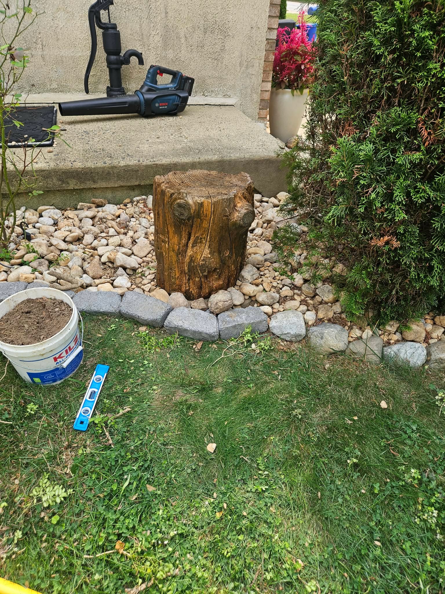 The finished stump set onto the concrete base in the garden, tools resting nearby